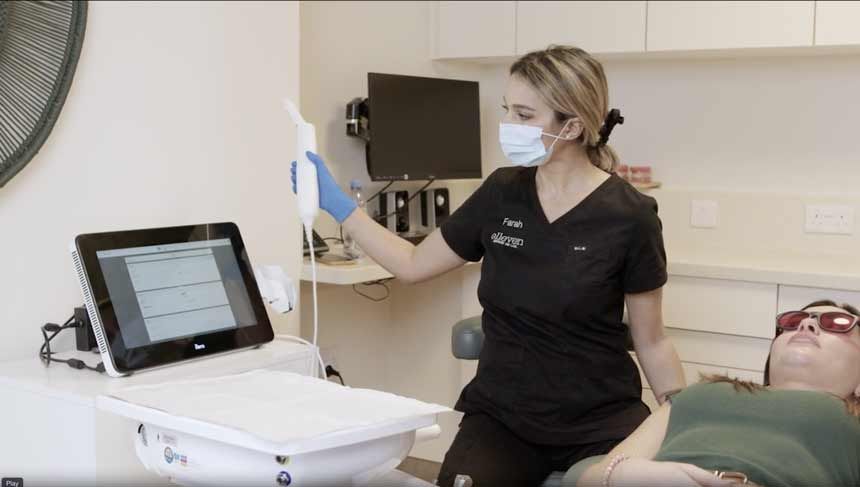 a woman wearing a mask is sitting in a dental chair next to a patient .