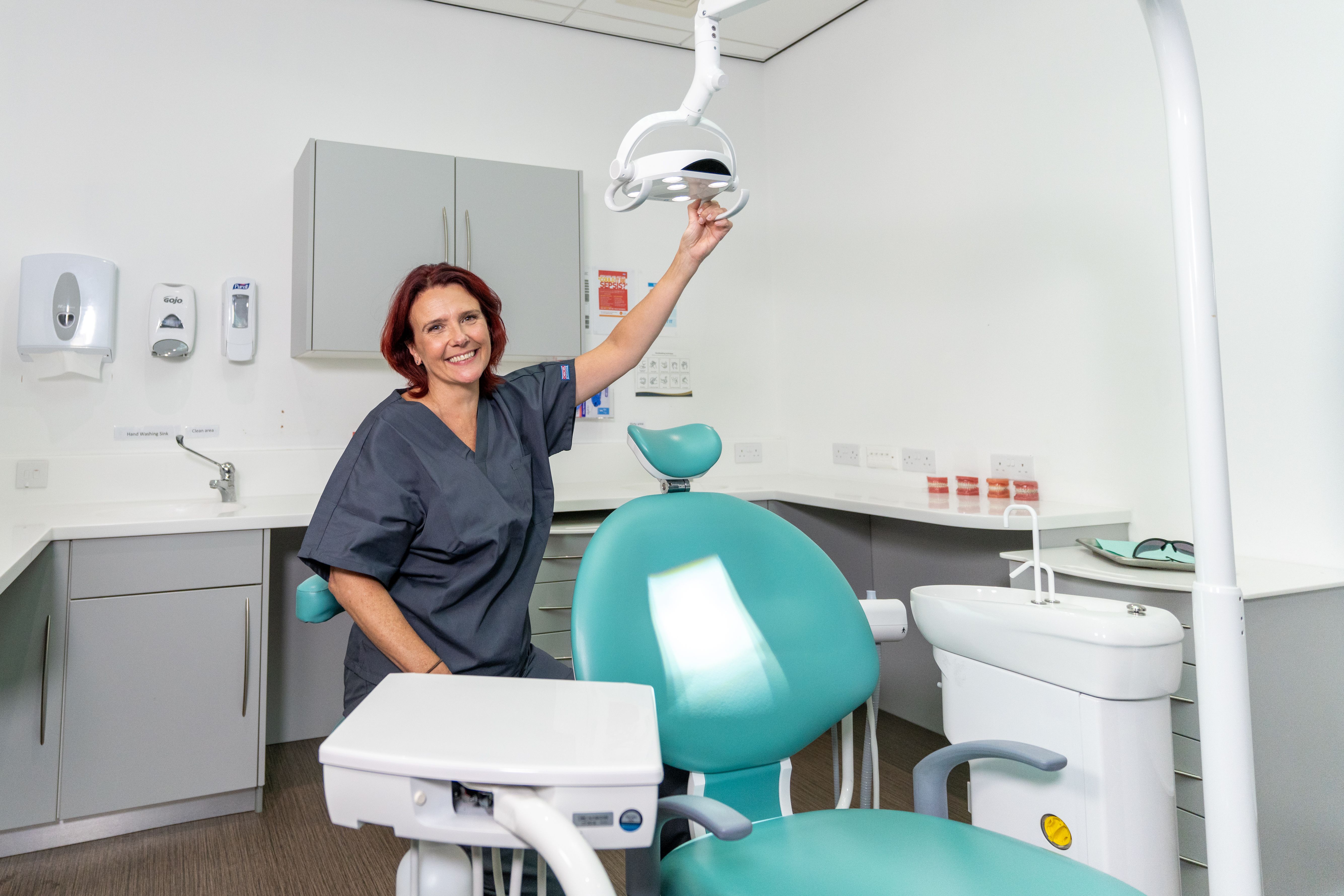 a woman is standing in a dental office holding a dental light .