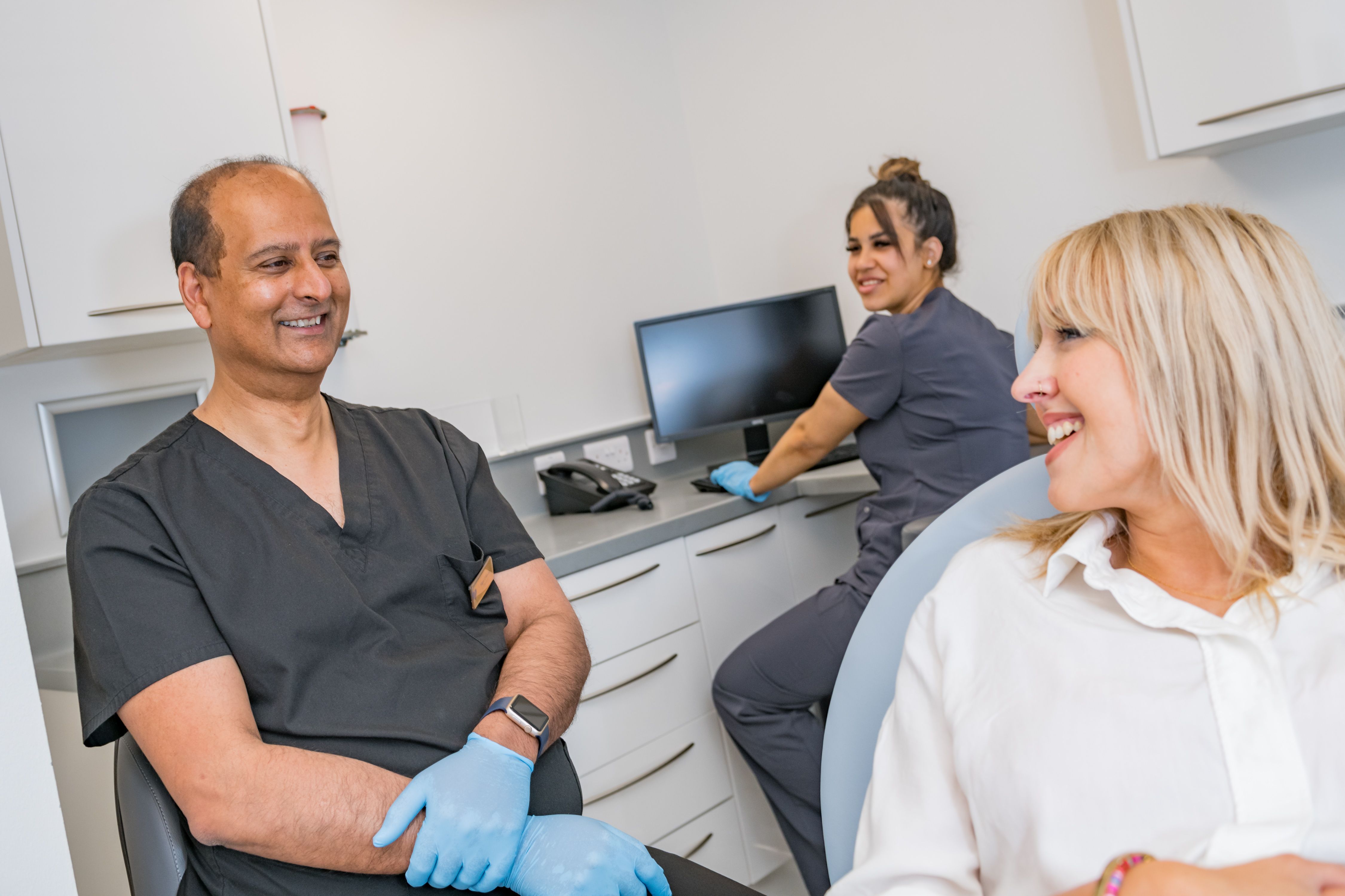 a woman is sitting in a dental chair talking to a dentist .