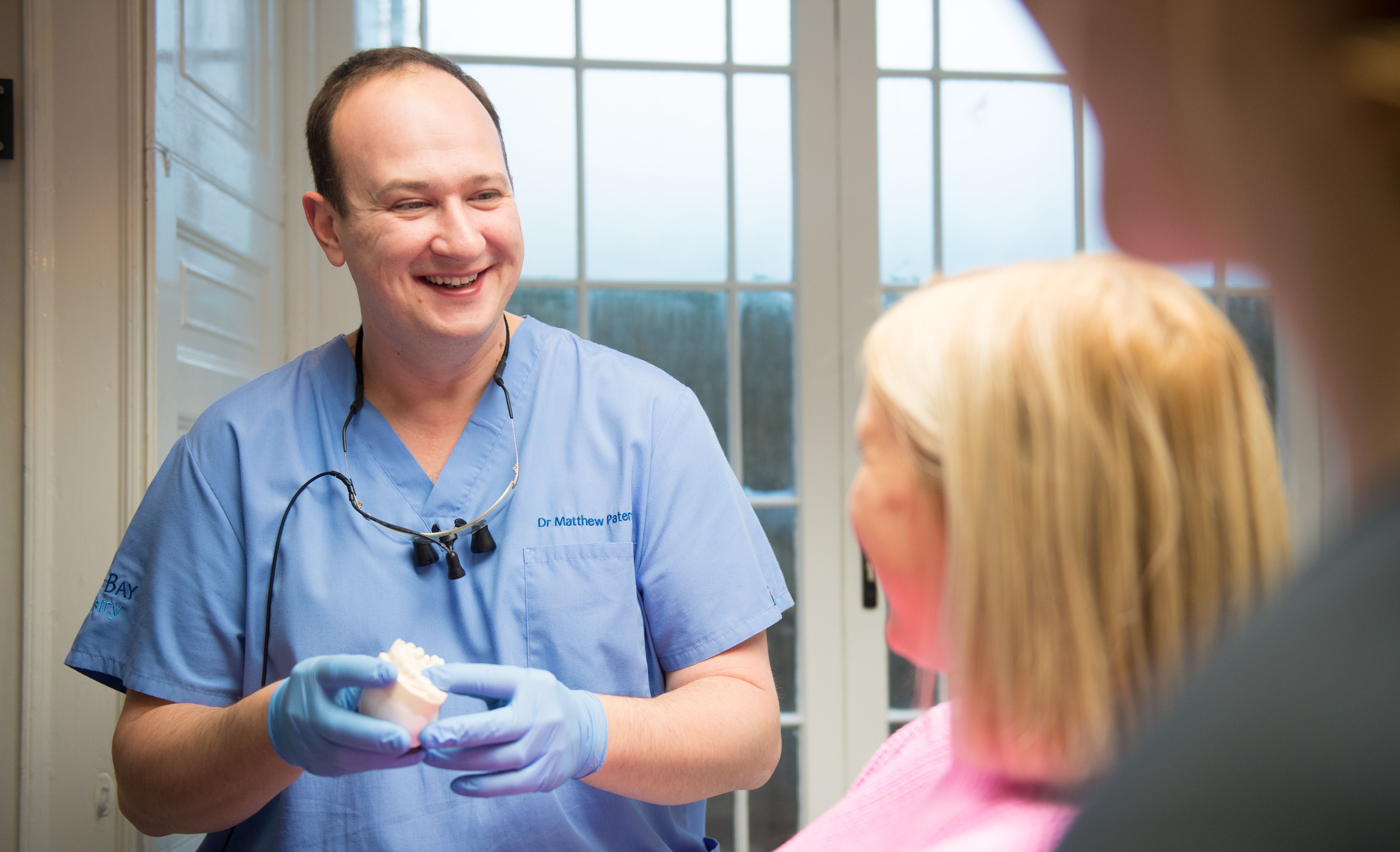 a dentist is smiling while talking to a patient in a dental office .