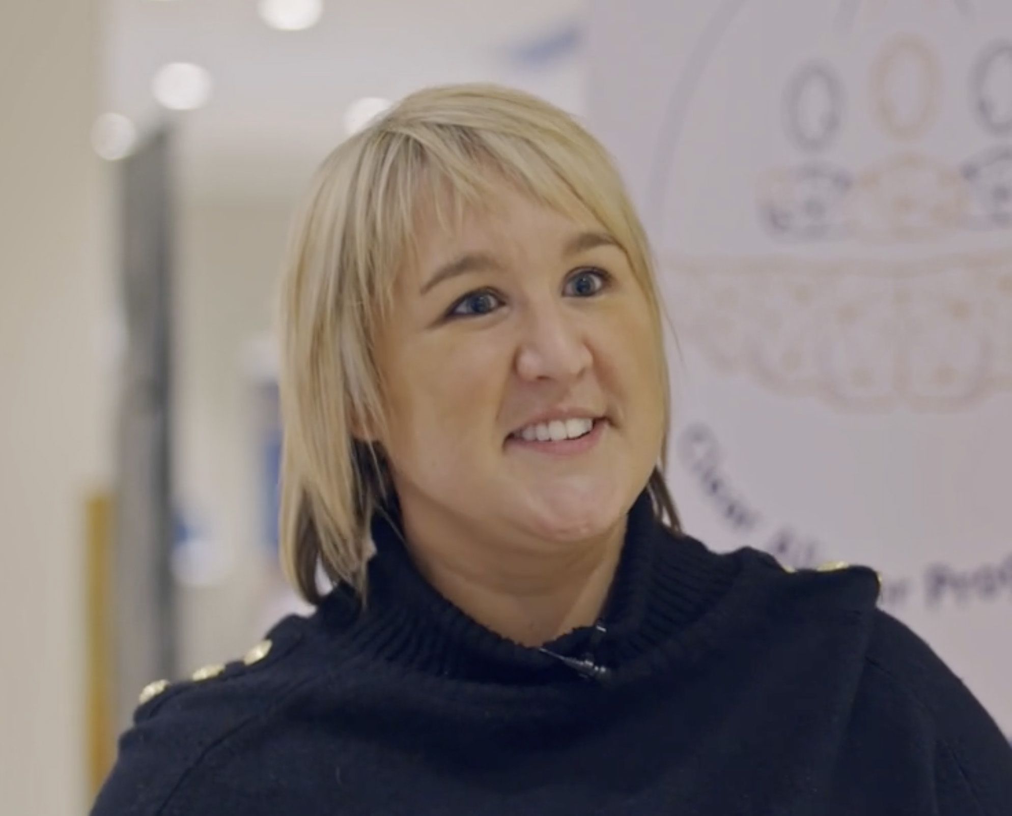 a close up of a woman wearing a black sweater and smiling .