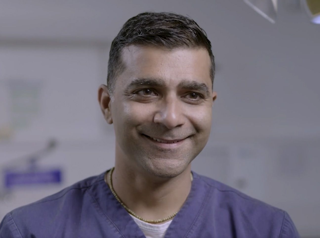a man in a purple scrub is smiling for the camera .