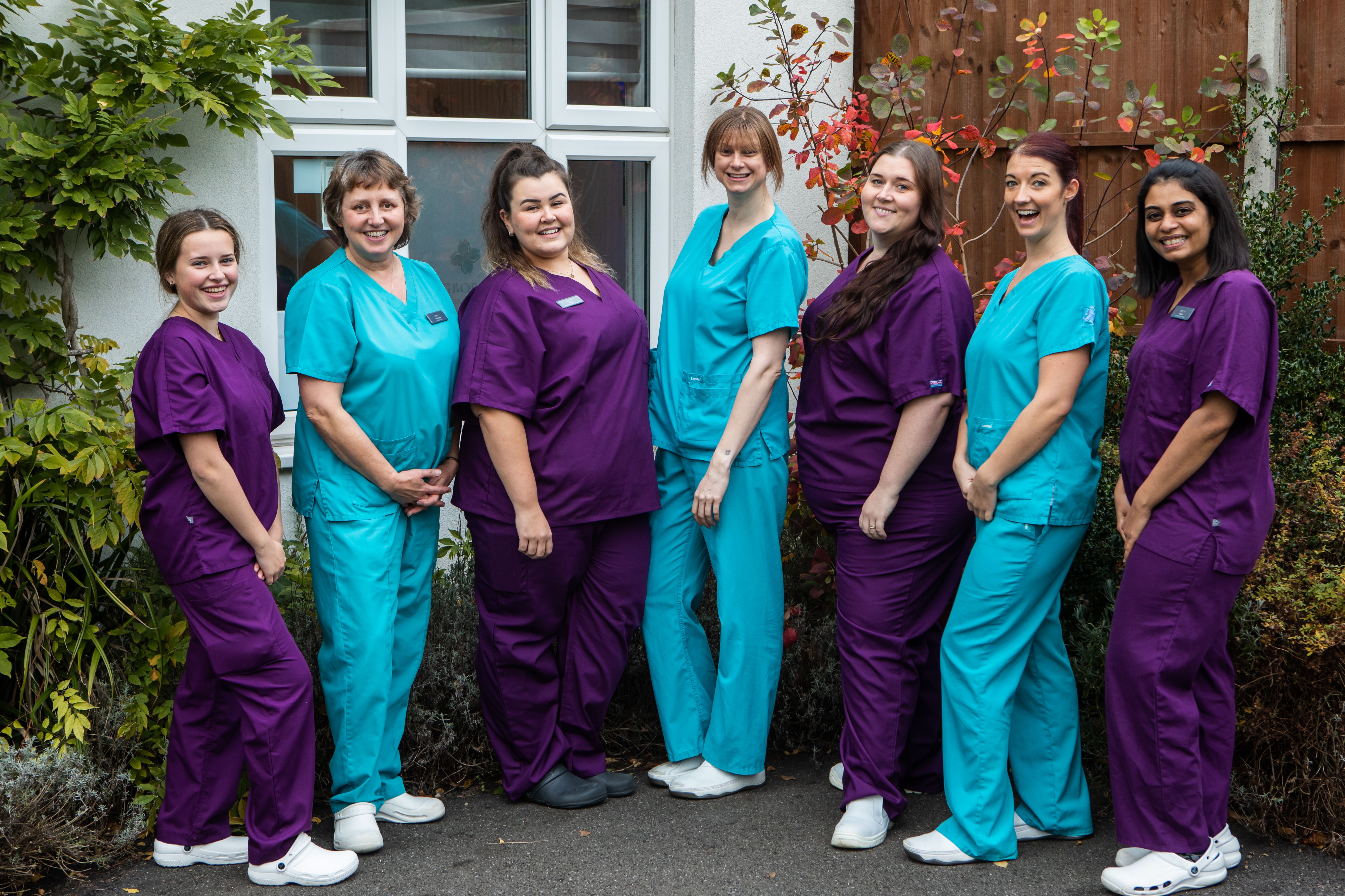 a group of women in scrubs are posing for a picture .