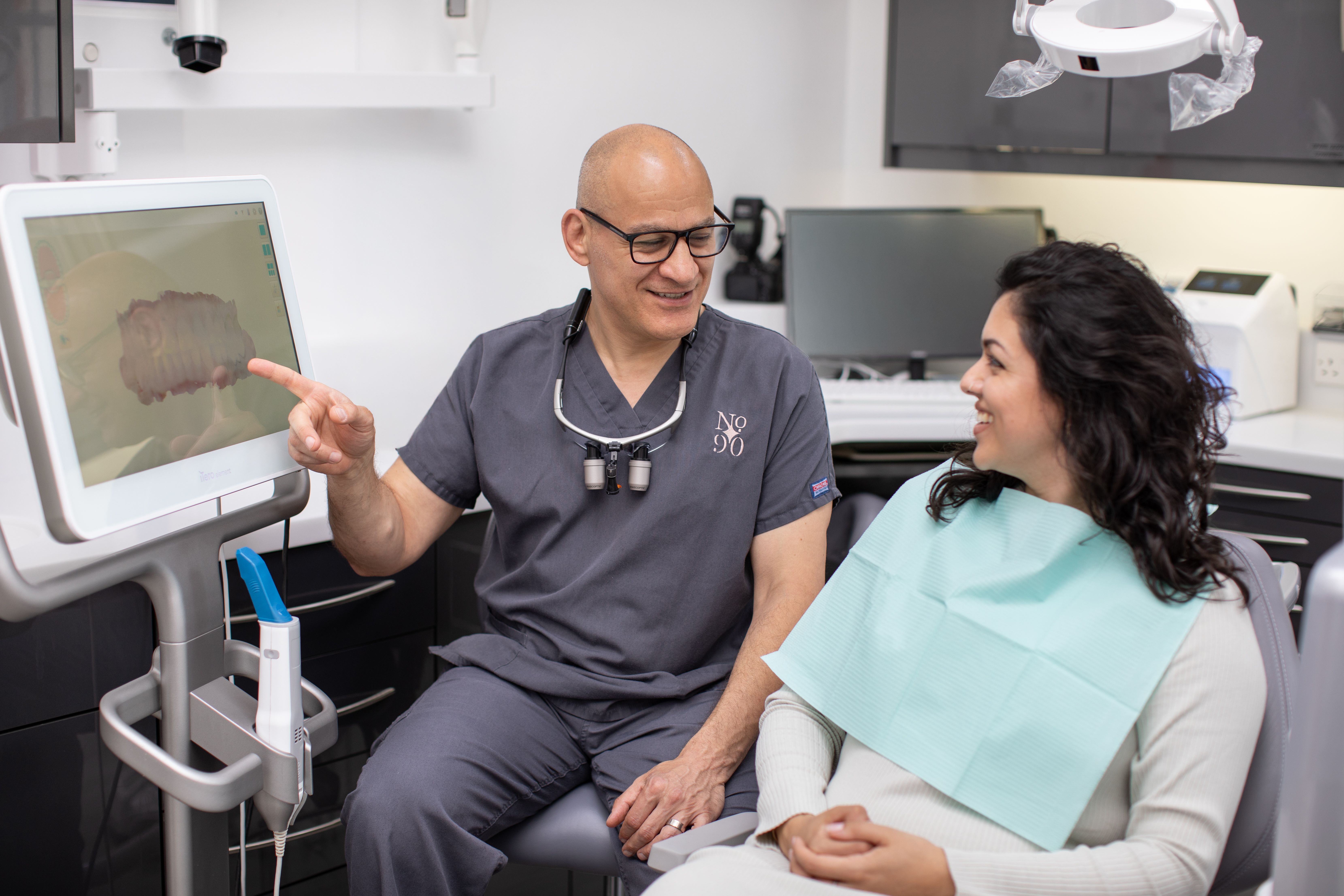 Dentist showing a smiling patient a digital scan of teeth on a monitor.