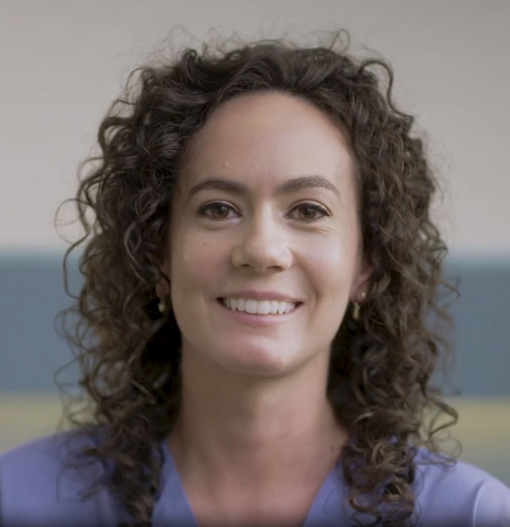a nurse is sitting in a chair in a hospital talking to a patient .