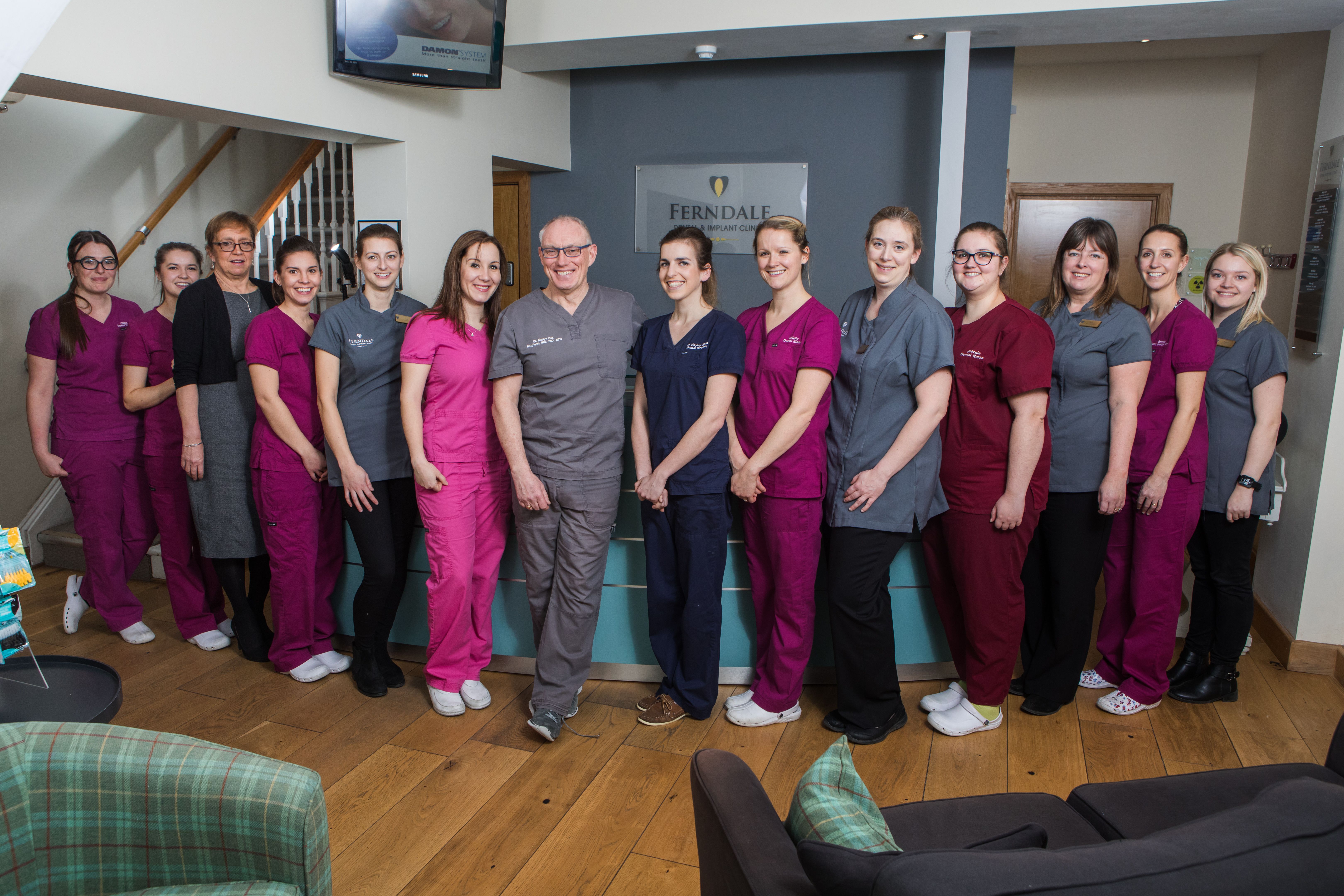 a group of people in scrubs are posing for a picture in a dental office .