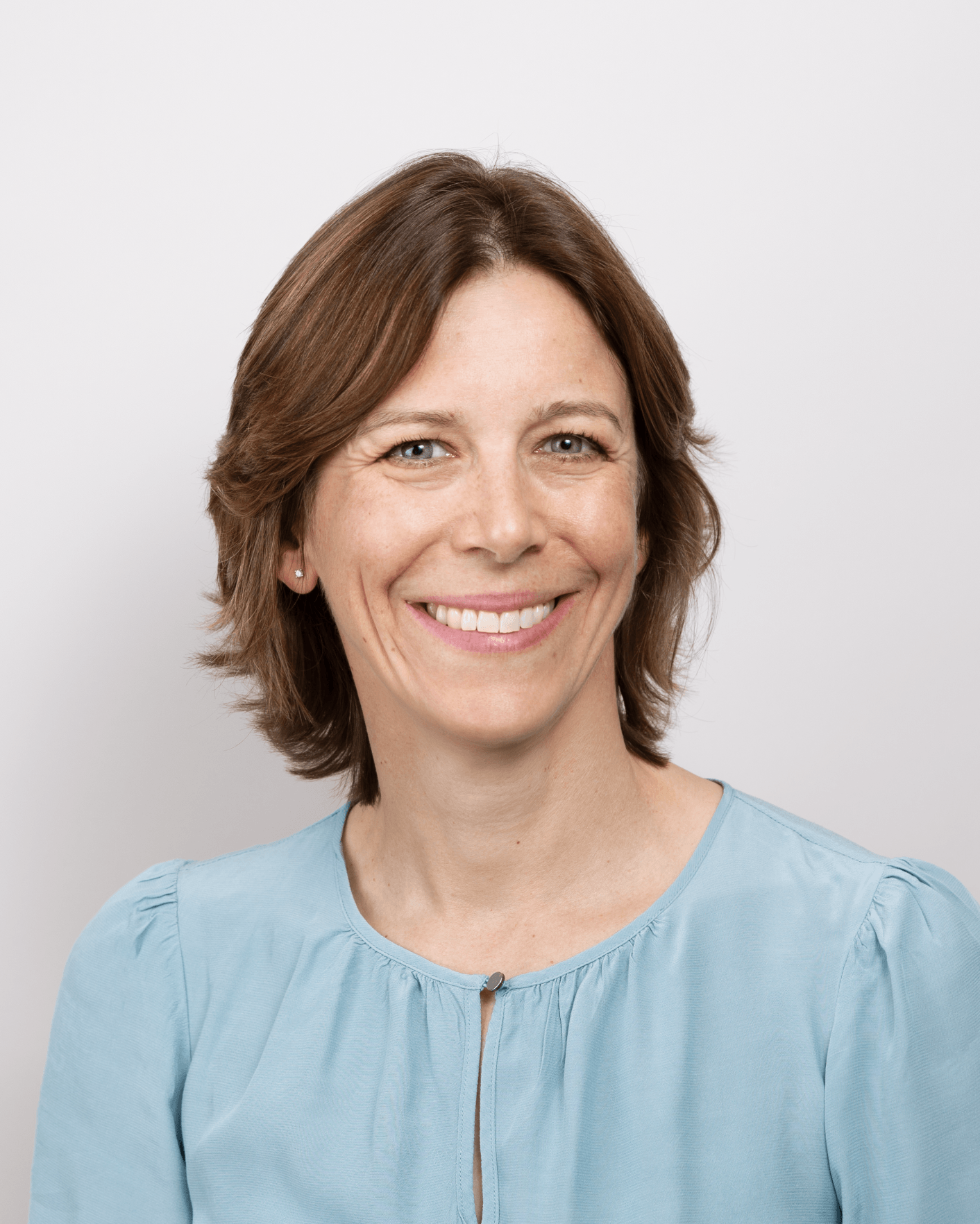 a woman in a blue shirt smiles for the camera
